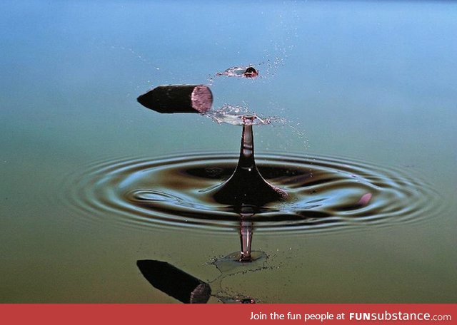 A bullet splitting a water droplet in half