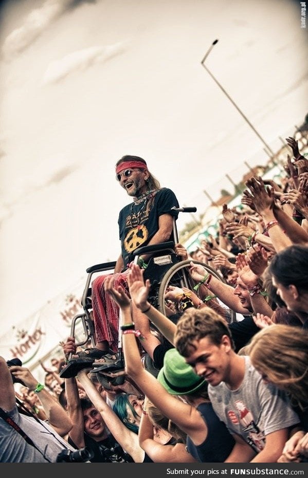 An old Hippie Crowd Surfing in His Wheelchair