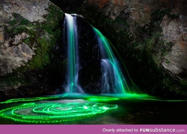 Long exposure shot of glowsticks dropped into a waterfall