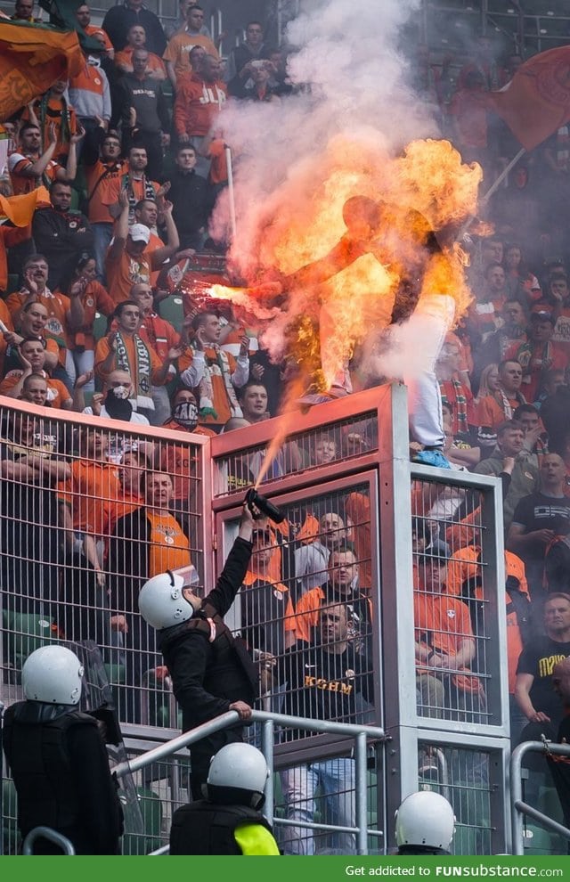 A Soccer fan, armed with a flare, was sprayed by police to prevent him from climbing over