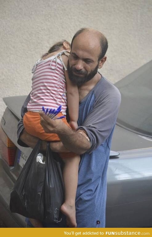 A Syrian father selling pens in Beirut while holding his sleeping daughter