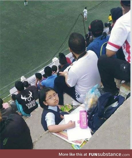 Daddy enjoys a football match while kiddo does homework. (Mizoram, India)