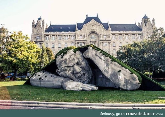 A giant sculpture crawls out of the ground in public square of budapest