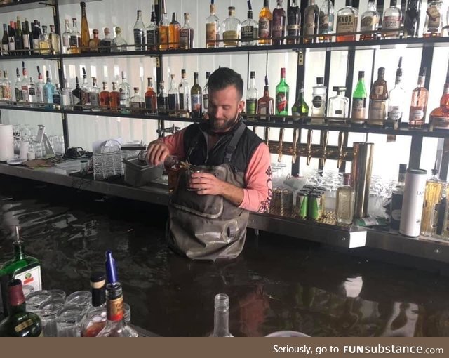 Owner pouring himself a drink after the rising Mississippi engulfed his bar in Davenport,