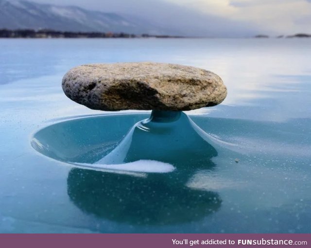 Rock on a frozen lake gets hot from the sun and melts the ice around it