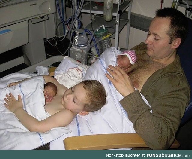 A big brother helping his father to give skin to skin contact to his premature twin