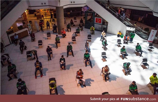 Food delivery drivers wait to pick up orders in “social distancing” chairs in