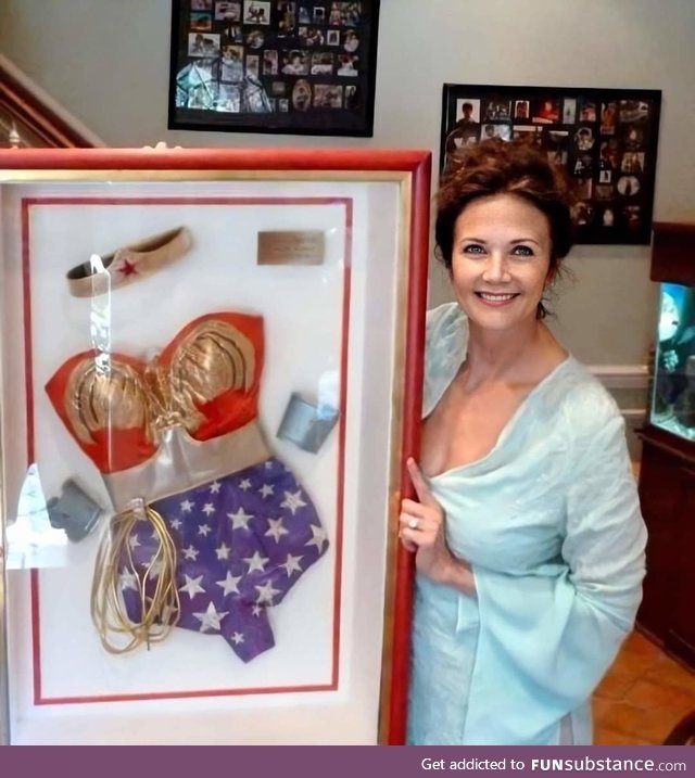 Lynda Carter posing with her old framed Wonder Woman costume