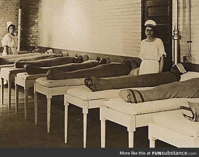 Nurses standing with mentally ill patients wrapped in wet linens. Thought to be calming