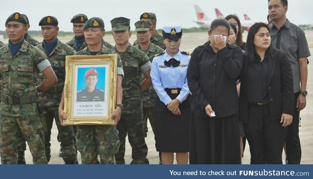 A guard holding a picture of Samarn Kunan, 38, a diver who died saving 13 lives in a