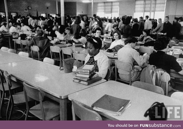 An African American student eating lunch alone after being newly integrated into a high