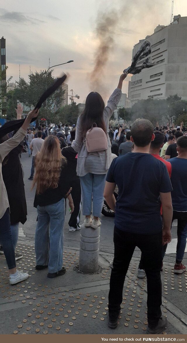 Young Iranian woman standing tall in the crown shouting for he freedom