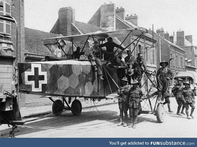 A downed German bomber being towed through a street by soldiers, likely from Australia,