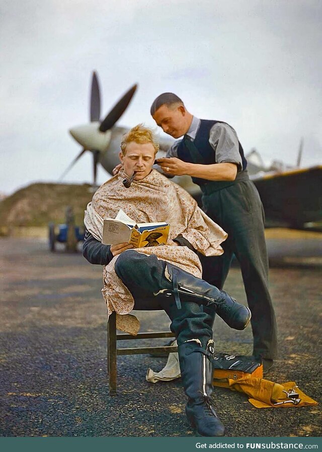 An RAF pilot getting a haircut during a break with a Spitfire in the background (1942)