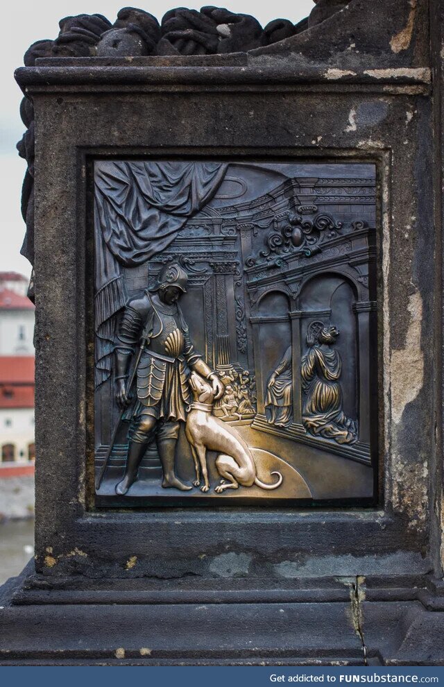 Carving of a dog glowing gold from people petting it for hundreds of years