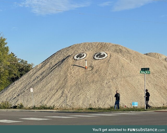 Someone periodically adds a face to this big gravel pile