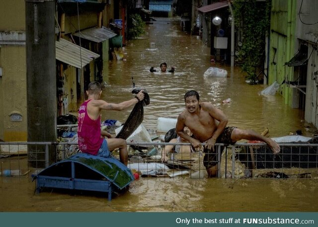 Residents of Manila climbing a fence to escape the flood caused by Typhoon Gaemi