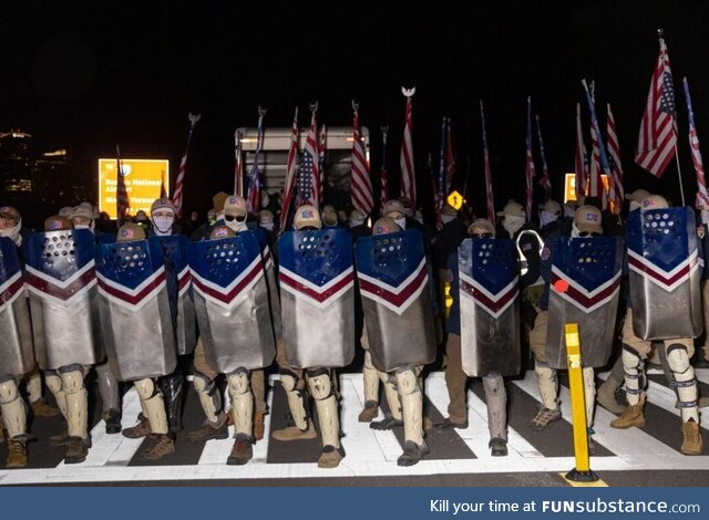 Members of the Patriot Front, a far-right group, hide behind shields after marching in