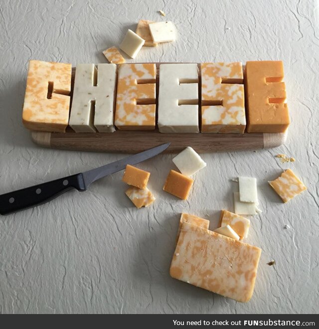 The word “CHEESE” carved out of cheese