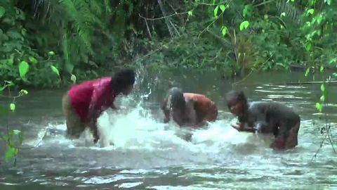 Baka women in Africa playing a river like drums