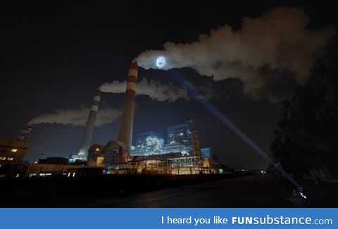 A sick child's face projected onto a factory smoke stack in China