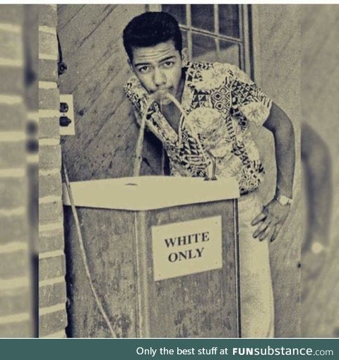 Stylish black man takes a sip from a "whites only" water fountain, 1960s