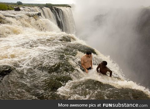 Two guys sitting near the edge of the Devil‘s Pool, Victoria Falls, Zambia