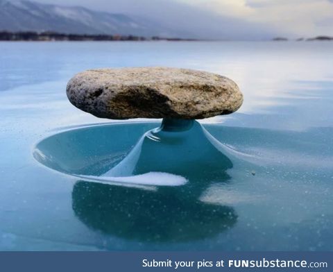 Rock on a frozen lake gets hot from the sun and melts the ice around it