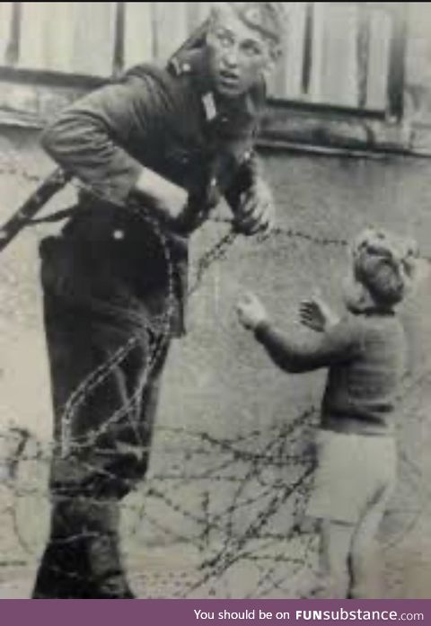 East German soldier letting boy through to reunite with his family