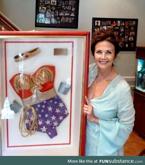 Lynda Carter posing with her old framed Wonder Woman costume