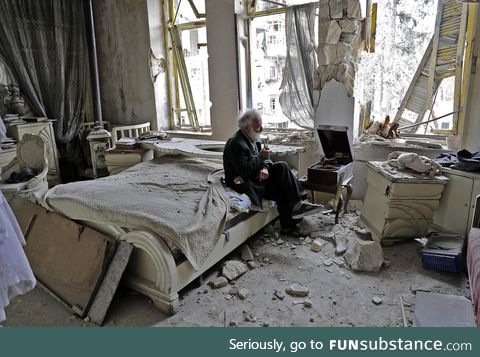 Syrian man listens to music on his hand-cranked gramophone in his destroyed bedroom,