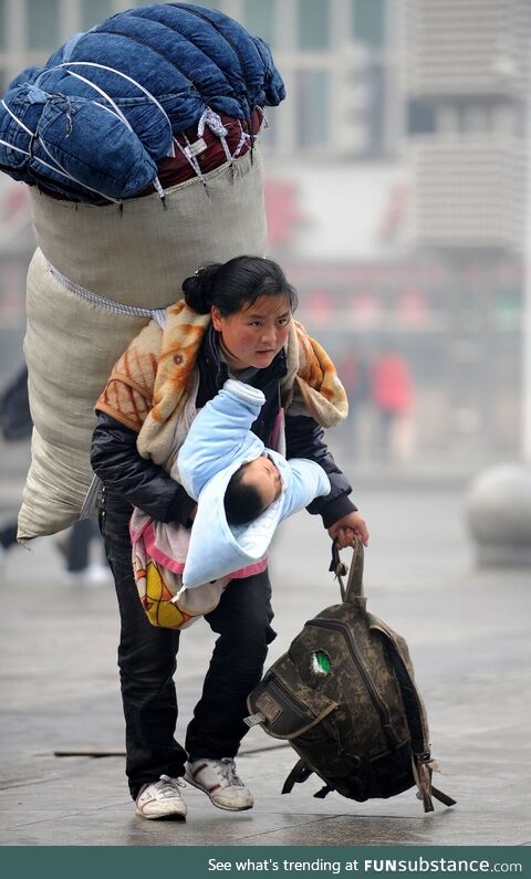 Luggage on her back and baby in her arm