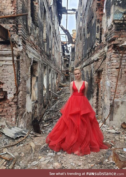 A graduate in her graduation dress on the rubble of her school destroyed by the Russian