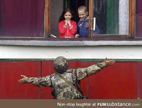 A Ukranian soldier cheers up children after freeing their city from Russian forces (2014)