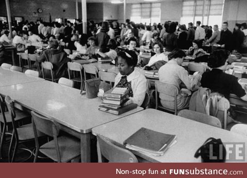 An African American student eating lunch alone after being newly integrated into a high