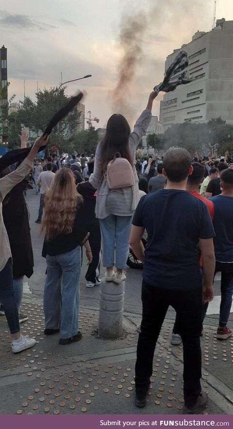 Young Iranian woman standing tall in the crown shouting for he freedom