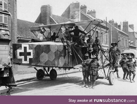 A downed German bomber being towed through a street by soldiers, likely from Australia,