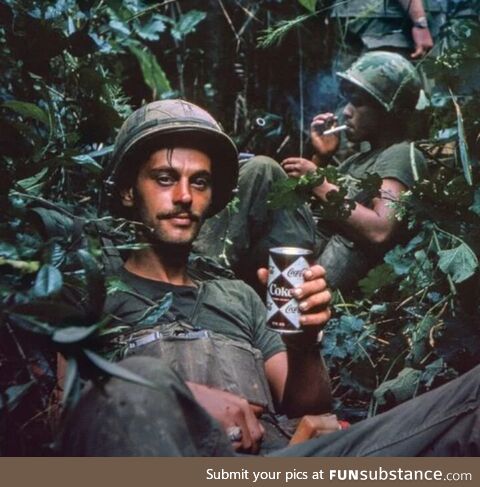 Drinking Coke while trapped in battlefield. Photo from 1970