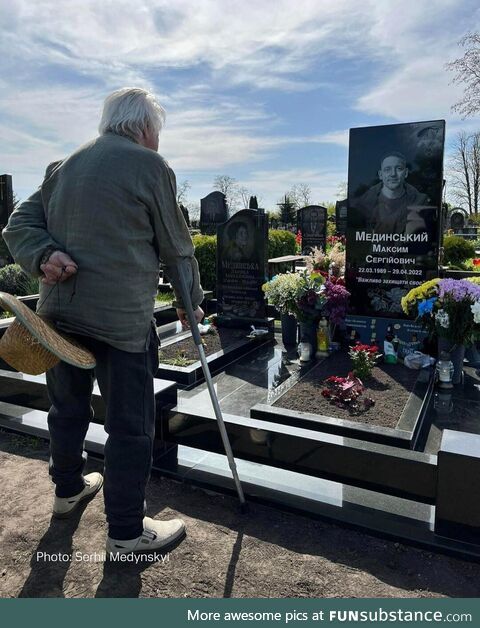 Grandfather standing next to the grave of his grandson, who was killed by Russians two