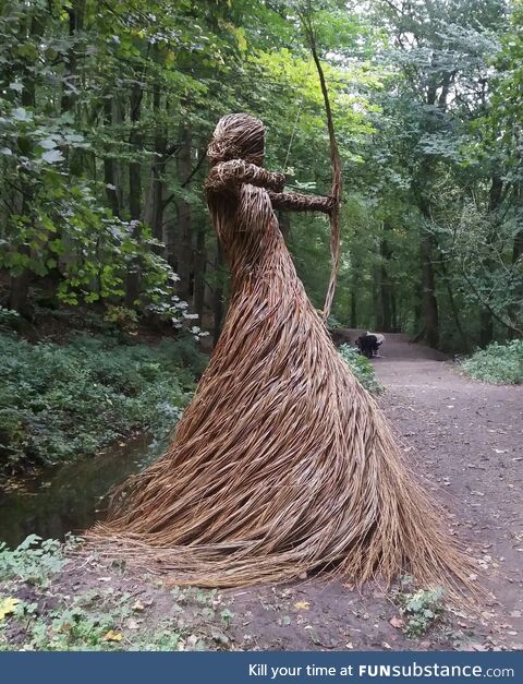 A stunning forest sculpture of a huntress made entirely from willow branches