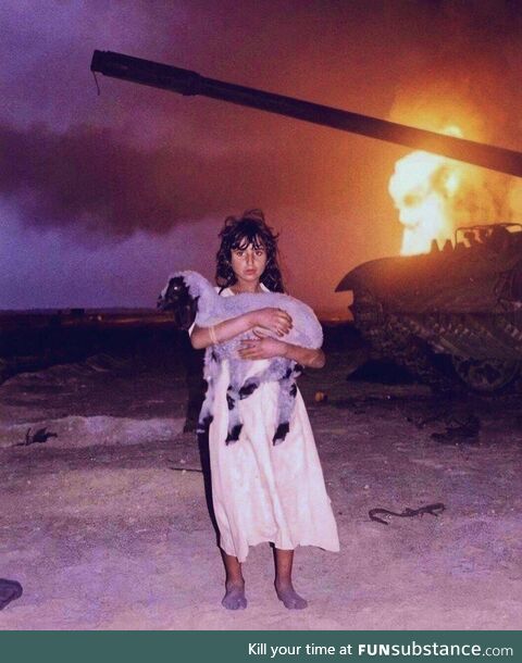 A photo of a young Bedouin Kuwaiti girl holding her lamb, during the Gulf War, (1991)