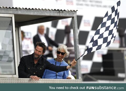 Motorcycle aficionado Keanu Reeves and Alexandra Grant wave the checkered flag at a race