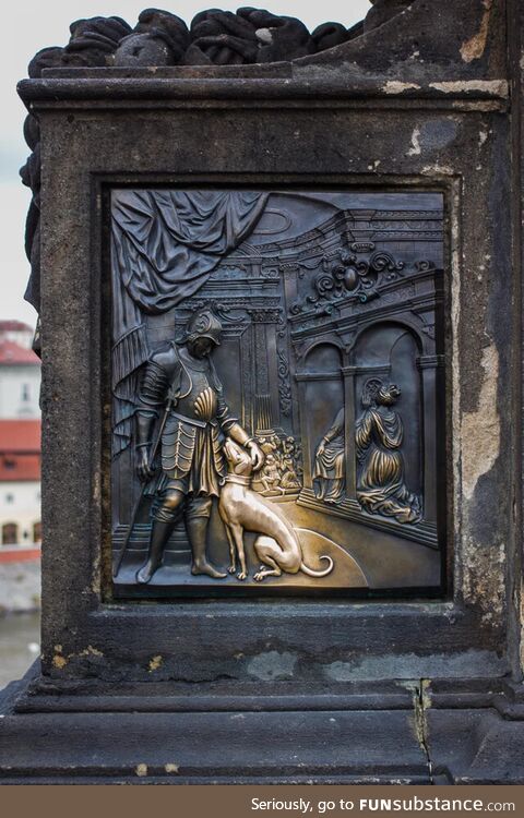 Carving of a dog glowing gold from people petting it for hundreds of years