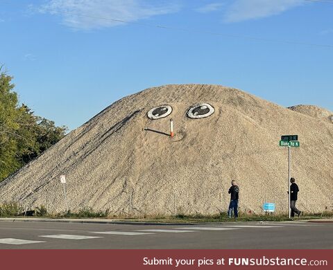 Someone periodically adds a face to this big gravel pile