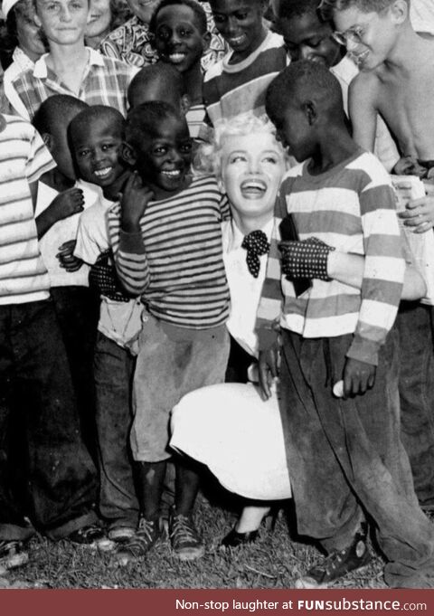 Marilyn Monroe embracing some children at a parade