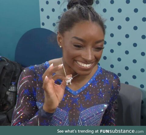 Simone Biles showing off a diamond-encrusted goat necklace after winning her 6th Olympic