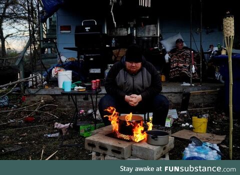 Tornado survivor sits by a fire outside his home to boil eggs and stay warm in Mayfield,