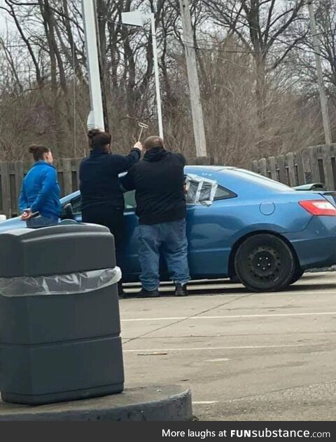 Three people trying to pick a lock to get the keys out. The rear window is already broken