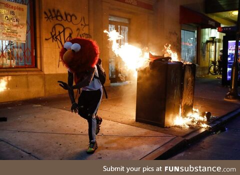 A protester in an Elmo mask dances as a street fire burns during a protest in Philadelphia