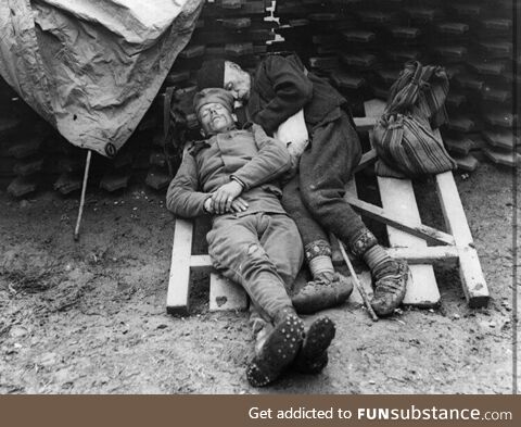 A Serbian soldier, taking a nap next to his father who came to visit him in the trenches